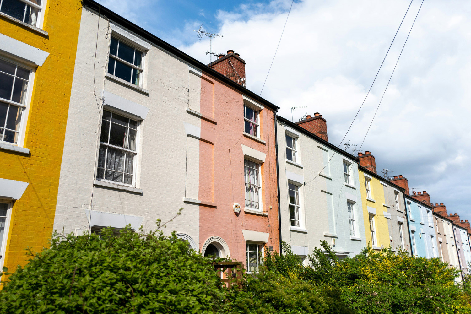 A row of colourful terraced houses under a blue sky with light clouds.
